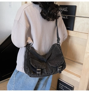 Detail of vintage washed denim messenger bag featuring large flap pockets and wide strap