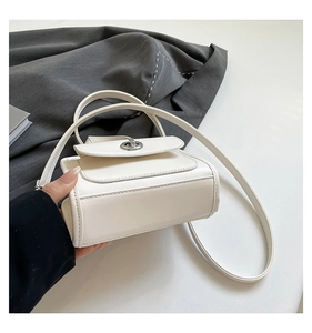 Detailed close-up of white crossbody bag with silver rotating lock and smooth leather texture