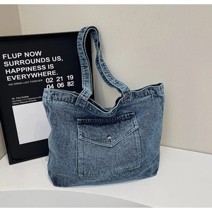 Detail of blue denim tote bag with functional utility pocket and silver snap button