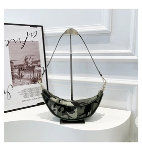 Detail of crescent moon sling bag with camouflage pattern and gold zipper on a stand
