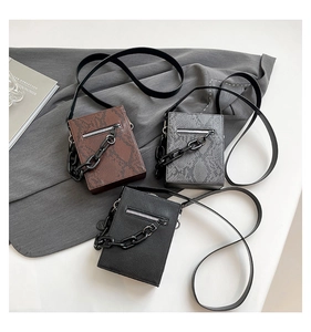 Detailed view of textured crossbody bags in snake print and black with matte chain decor