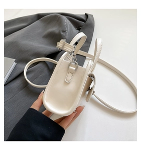 Side view of cream-colored leather handbag showing metal buckle and compact structure