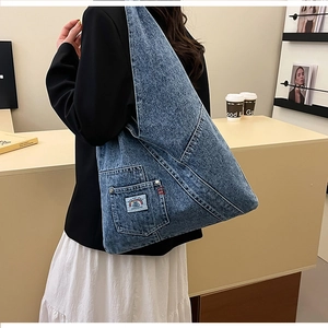 Detailed view of blue denim tote bag featuring a stitched pocket and rainbow patch