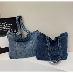 Detail of vintage denim tote bag showing metal buckle pockets and washed fabric texture