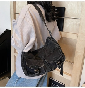 Detailed view of charcoal gray washed denim messenger bag with vintage buckle straps