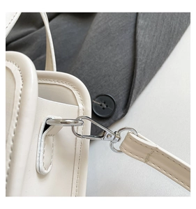 Detailed close-up of cream leather bag featuring silver metal D-ring and lobster clasp