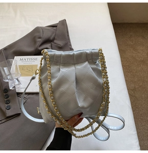 Detail view of the quilted light blue bucket bag featuring a gold chain leather strap