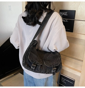 Detail of black washed denim biker bag featuring vintage cargo pockets and metallic buckles