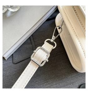 Detail of cream white leather shoulder strap with silver metal buckle and swivel hook