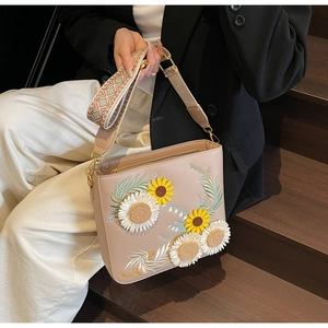 Detail of floral embroidery on pink leather shoulder bag with jacquard strap