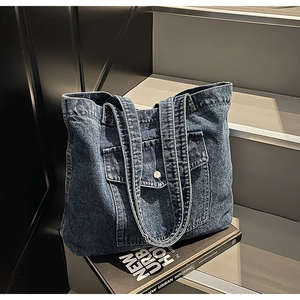 Detailed close-up of dark blue denim tote bag texture with front pocket on grey stairs
