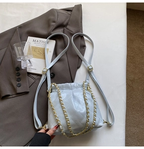 Detail of light blue quilted leather bag with gold chain strap and drawstring closure