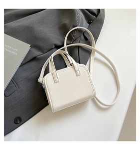Detail of a white leather briefcase bag with top handles and silver metal hardware