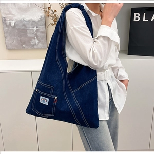 Detailed side view of vintage denim tote bag with functional pockets and white stitching