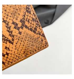 Close-up of orange snake pattern leather texture with fine stitching on women handbag