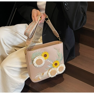 Detail of beige tote bag featuring floral sunflower embroidery and bohemian strap