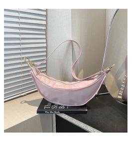 Detail of pink crescent moon shoulder bag with glossy texture and gold metal zipper