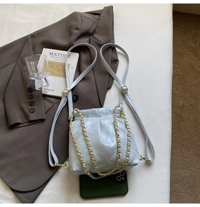 Detailed view of light blue quilted leather backpack with gold chain drawstring closure