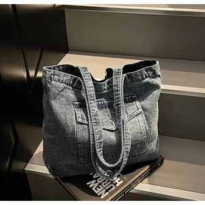 Detail of vintage blue denim tote bag with metal buckle pocket on urban housing book