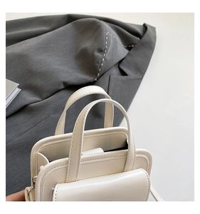 Detailed macro view of white PU leather texture and premium stitching on a handbag