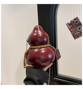 Macro view of the deep red gourd-shaped leather bag with silver chain and woven rope