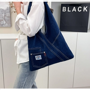 Detailed close-up of dark blue denim tote bag with cross-stitch and Into The Space label