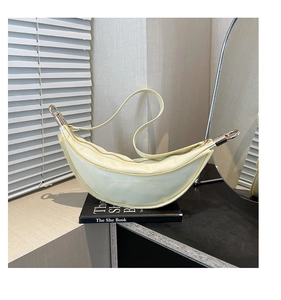 Detailed macro view of the smooth light yellow leather finish and gold zipper on crescent bag