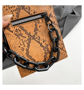 Close-up of orange snakeskin texture with black thick chain and zipper detail