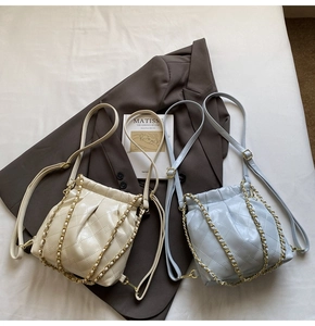 Detail of quilted bucket bag with gold chain and drawstring in cream and light blue