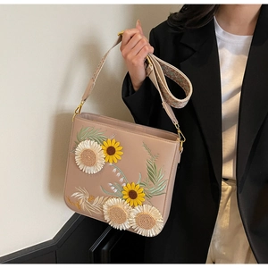 Detail of floral embroidery on a shoulder bag with sunflower and jacquard strap
