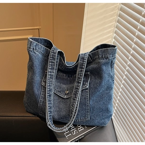 Detail of vintage denim tote bag featuring a front flap pocket and metal buckle closure