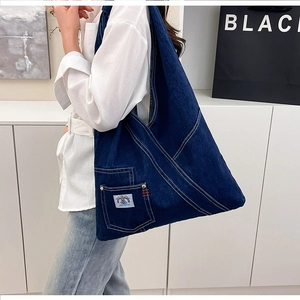 Detailed view of deep blue denim shoulder bag with retro embroidery and large side pocket
