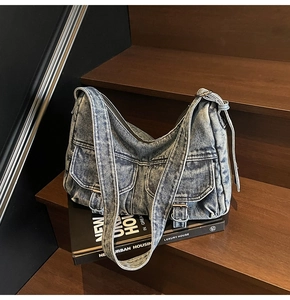 Detailed view of washed denim bag featuring vintage pockets and metal buckle hardware