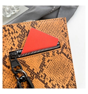 Close-up of orange-brown snakeskin texture with black chain zipper and red accessory