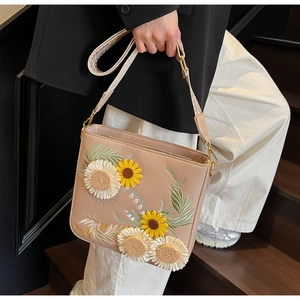 Detail of floral embroidery and bohemian strap on beige crossbody shoulder bag