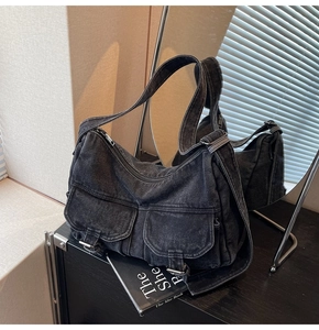 Detail of dark grey washed denim shoulder bag with cargo pockets and metal buckle hardware