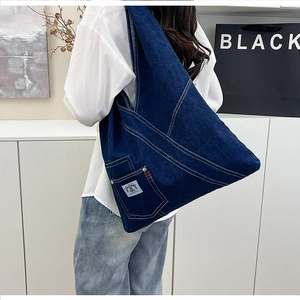 Macro detail of dark blue denim tote bag with white contrast stitching and woven label