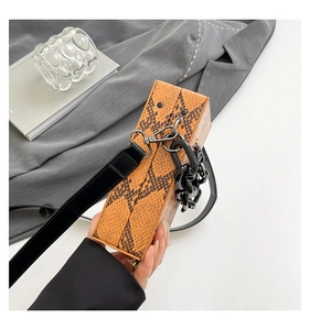 Detail of orange snake pattern leather on a structured box bag with black chain strap