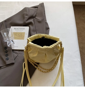Detailed top view of light yellow quilted bucket bag with chain strap and magnetic closure