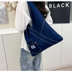 Detail of vintage blue denim tote bag featuring white contrast stitching and a side pocket