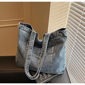 Macro shot of the light blue washed denim tote bag with front pocket on a bench