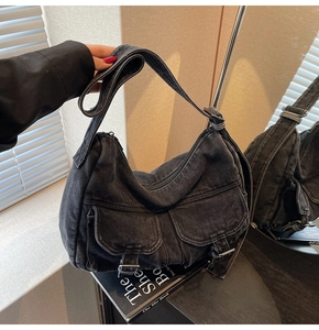 Close-up of black denim hobo bag with vintage utility pockets and silver metal buckles