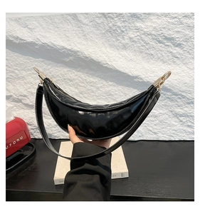 Close-up of a glossy black crescent dumpling bag with polished silver metal hardware