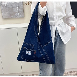 Detail of deep blue denim tote bag with visible stitching and brand woven label