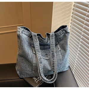 Detailed view of washed blue denim tote bag with front flap pocket and metal buckle