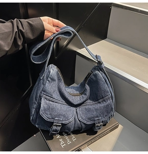 Detail of vintage blue denim biker bag with dual front pockets and silver metal hardware