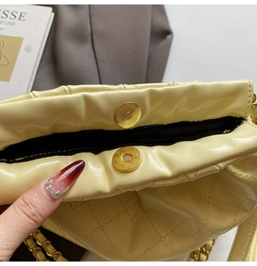 Close-up of golden magnetic clasp and quilted yellow leather detail on crossbody bag