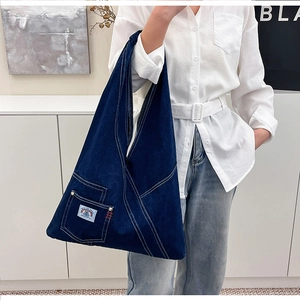 Macro shot of dark blue denim tote bag with contrast white stitching and side patch pocket
