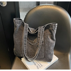Close-up of vintage grey denim tote bag with white stitching on a black chair