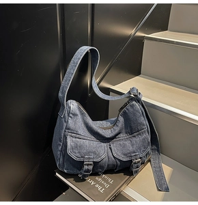 Detailed macro view of vintage denim shoulder bag with metal buckles and washed denim texture